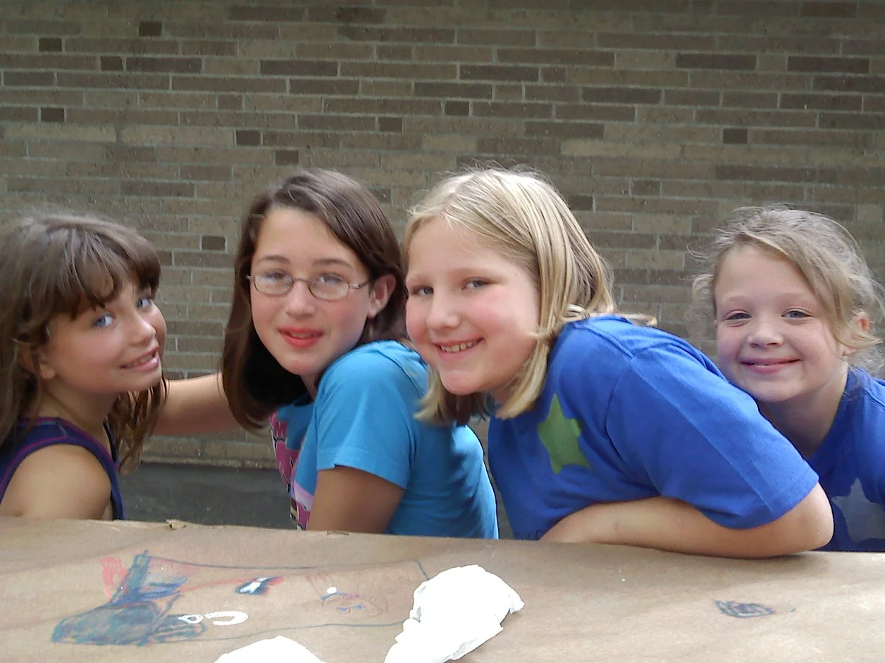 girls sitting around a table at camp